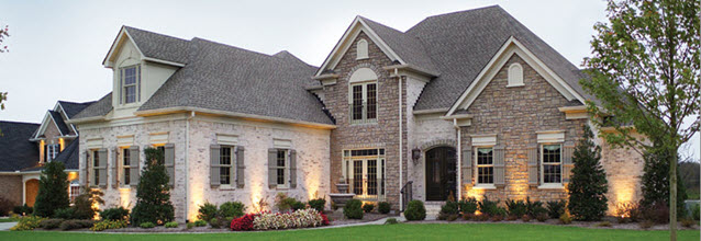 Weather Shield windows installed in a large, stone-front home with landscaped front lawn.