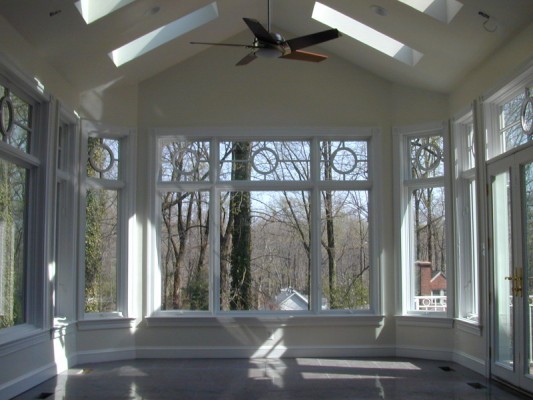 Tall white triple-pan windows installed in a sunroom with vaulted ceilings and skylights.