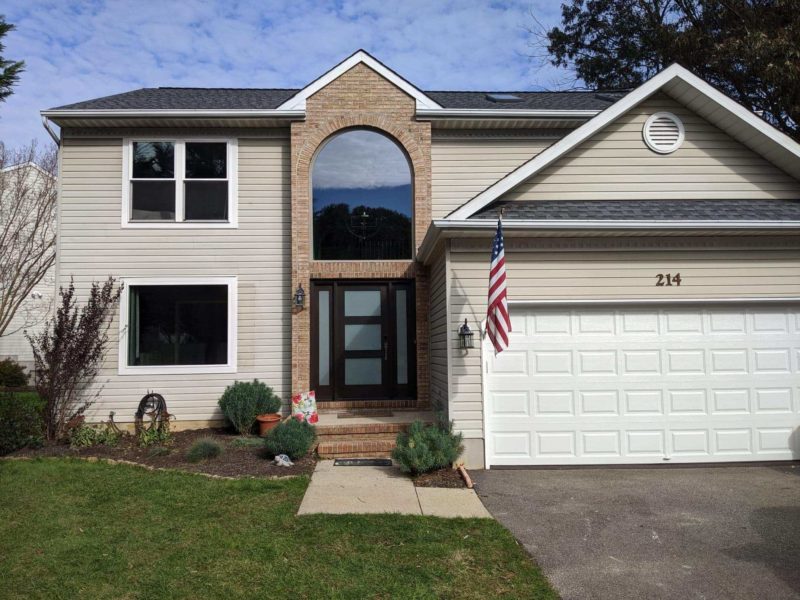 Two-story home with large arched picture window in second story.