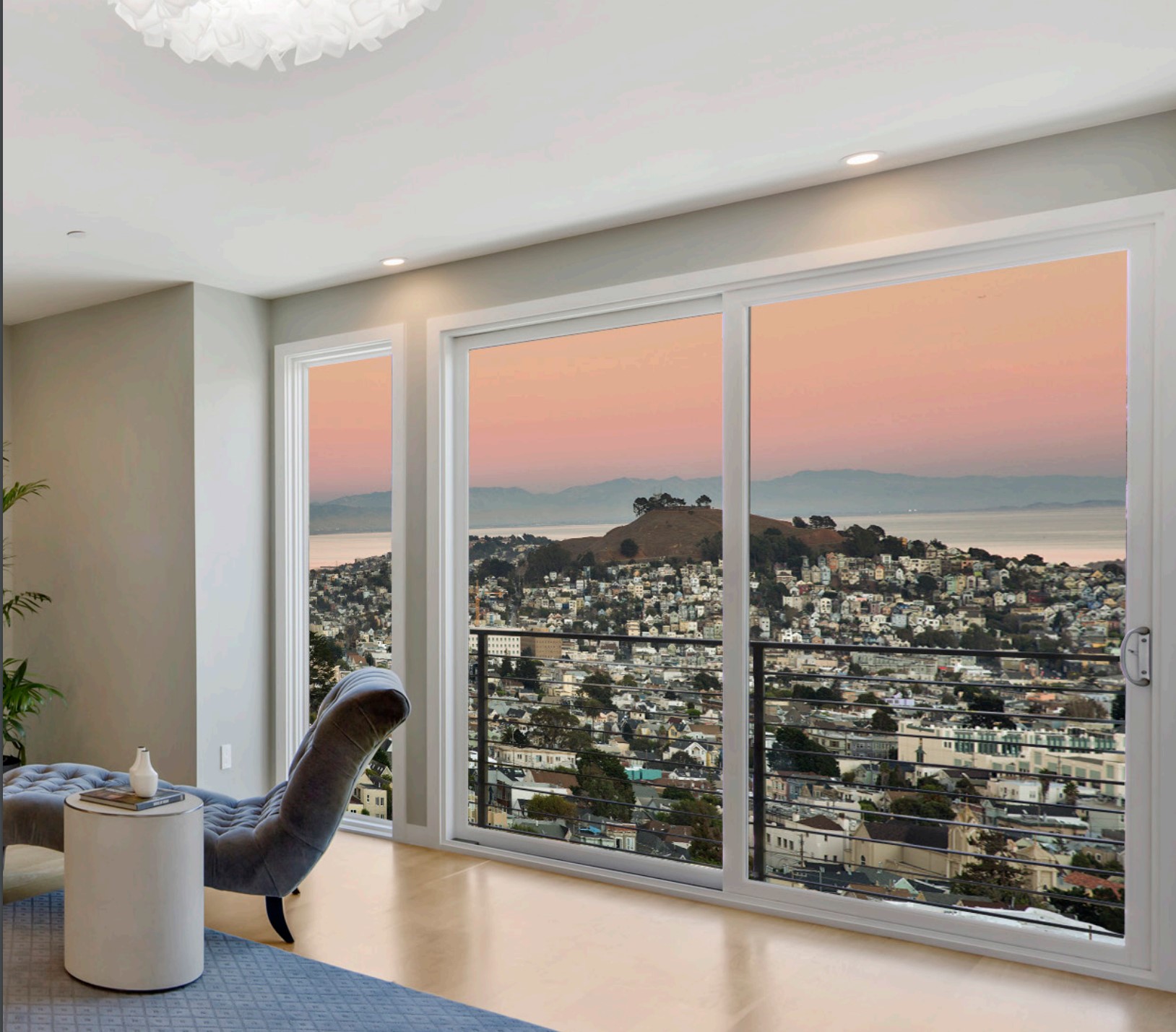 Large set of wall-size white-framed windows with view of a city at sunset.