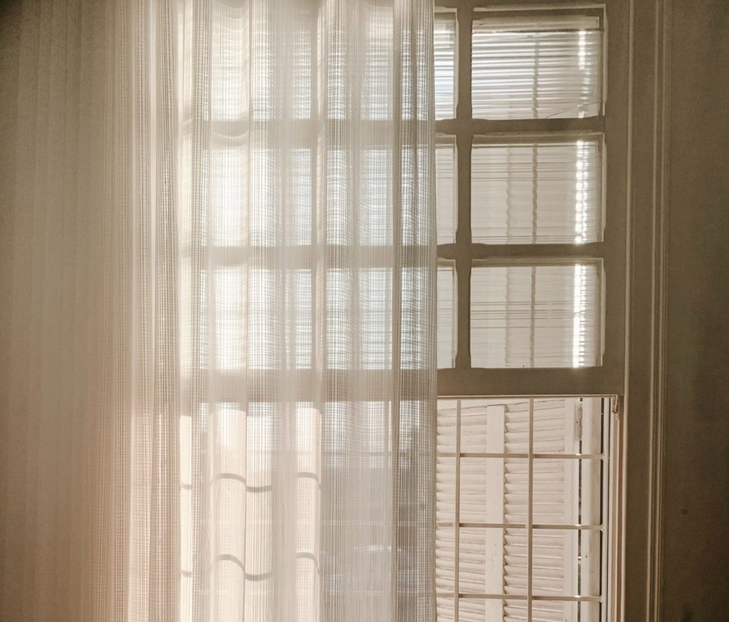 Cheap double-hung window with a curtain partially covering it.