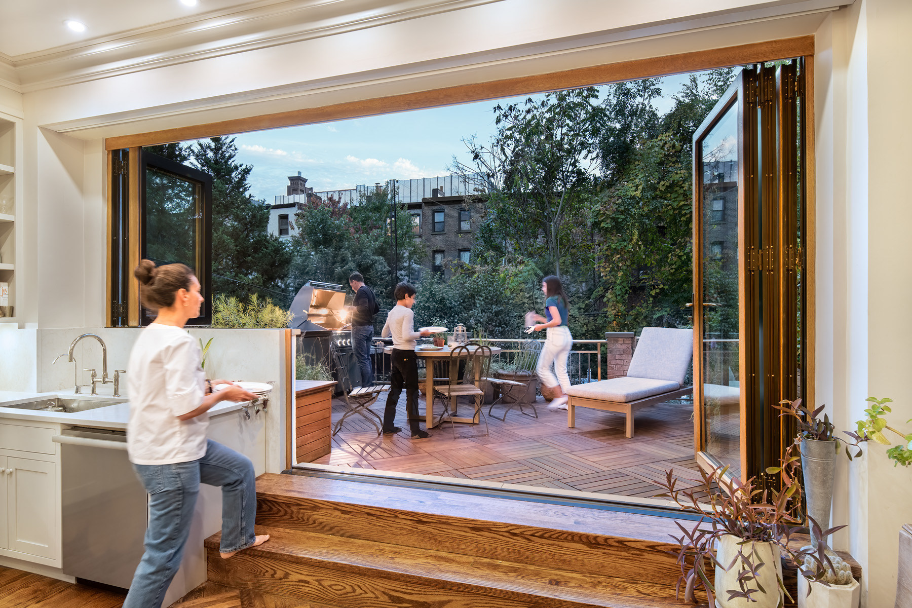 Man walking through kitchen toward patio; NanaWall windows open to make the space transitional.